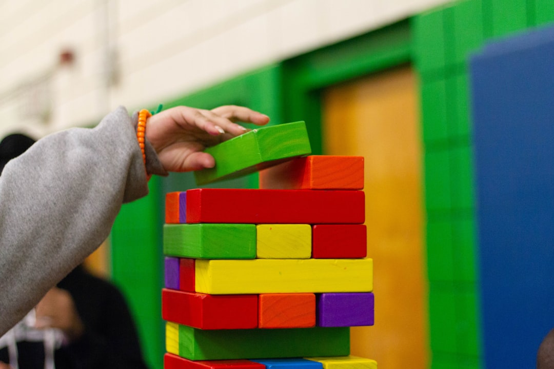 Child's hand building a tower of coloured wooden blocks