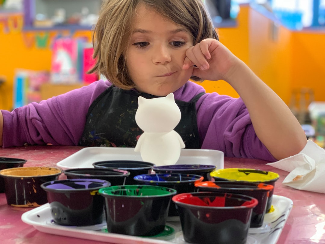 Girl concentrating over jars of tempera paints