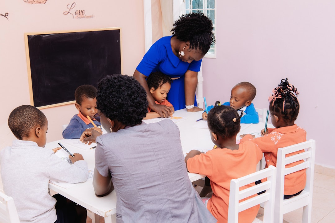 Teacher helping a group of young children draw at a table